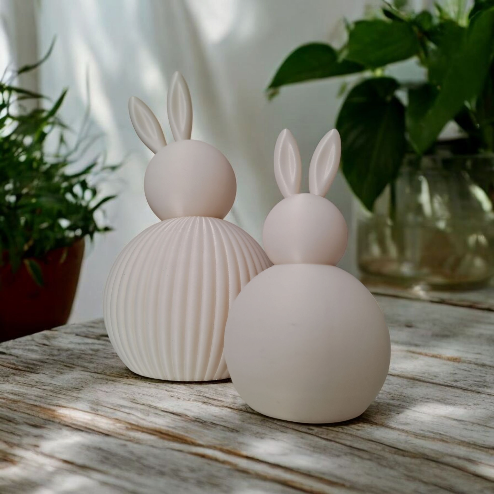 Minimalistiske hvide påskeharer placeret på et dækket bord med forårsstemning.