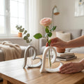 To hjerteformede vaser i nordisk design med rose og grøn gren i stue med blødt lys og rolige farver