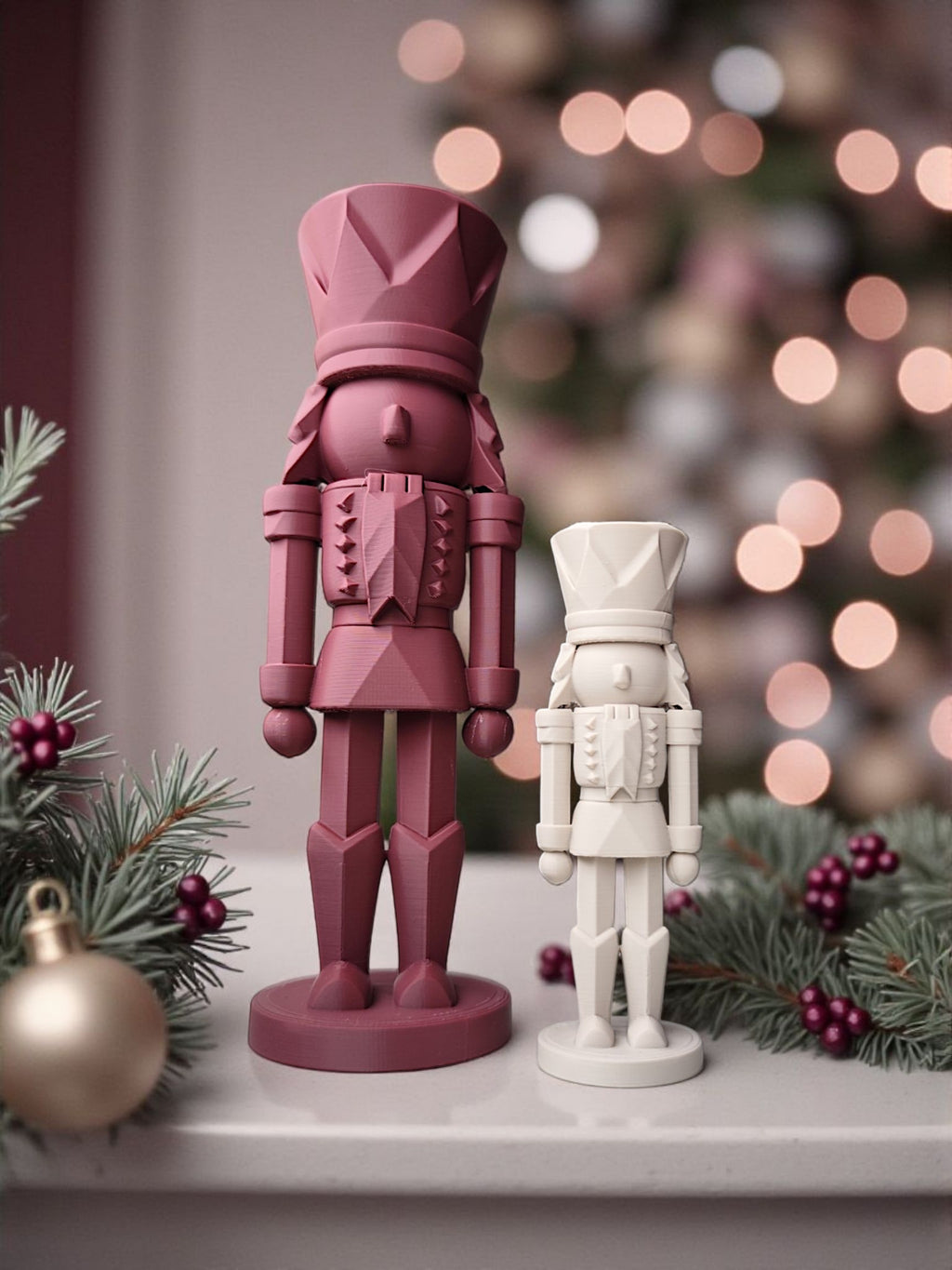 Stor rød og lille hvid 3D-printet nøddeknækker figur foran juletræ og grangrene med pynt.